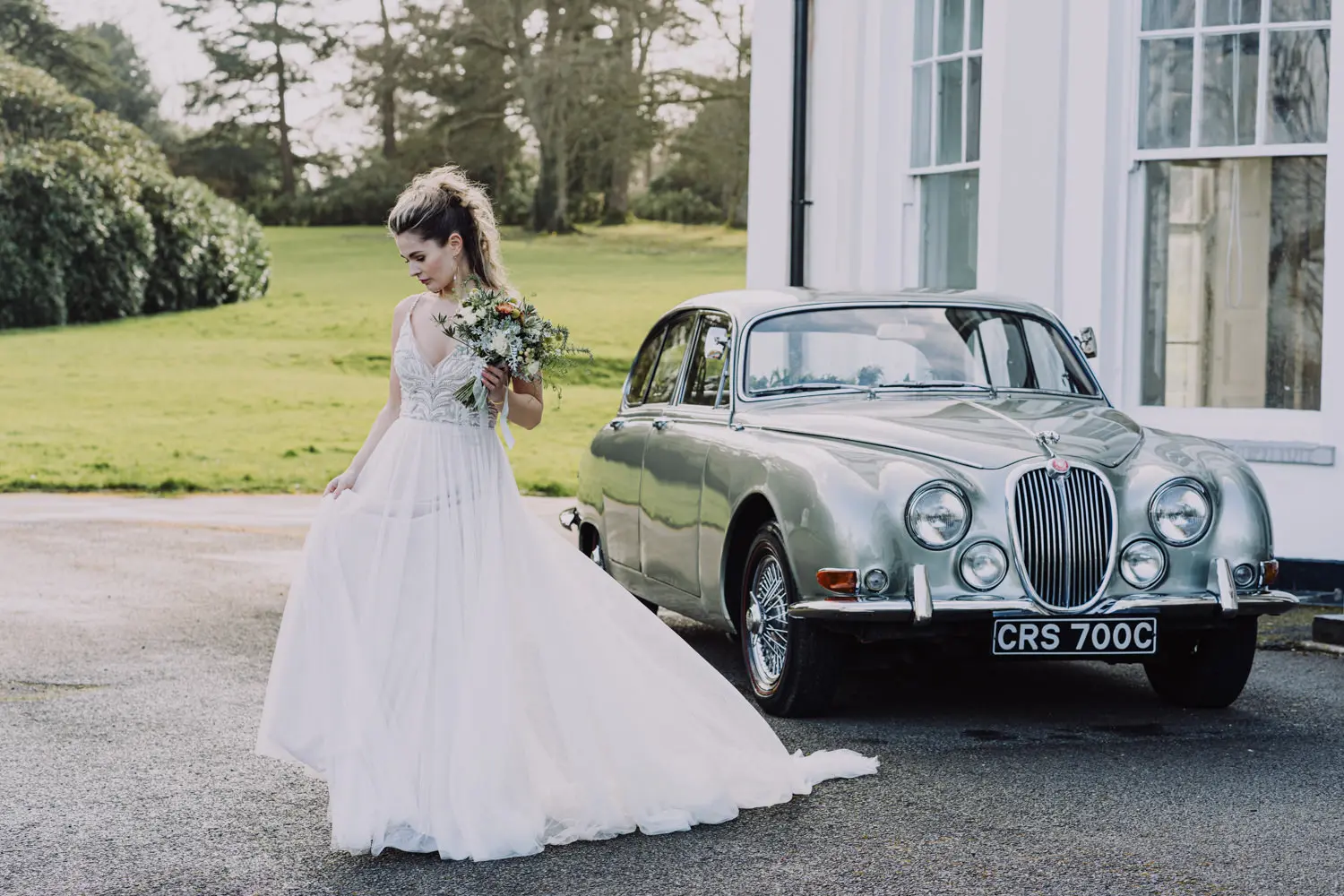 moreton house wedding venue in North Devon, Bride with bouquet next to classic car