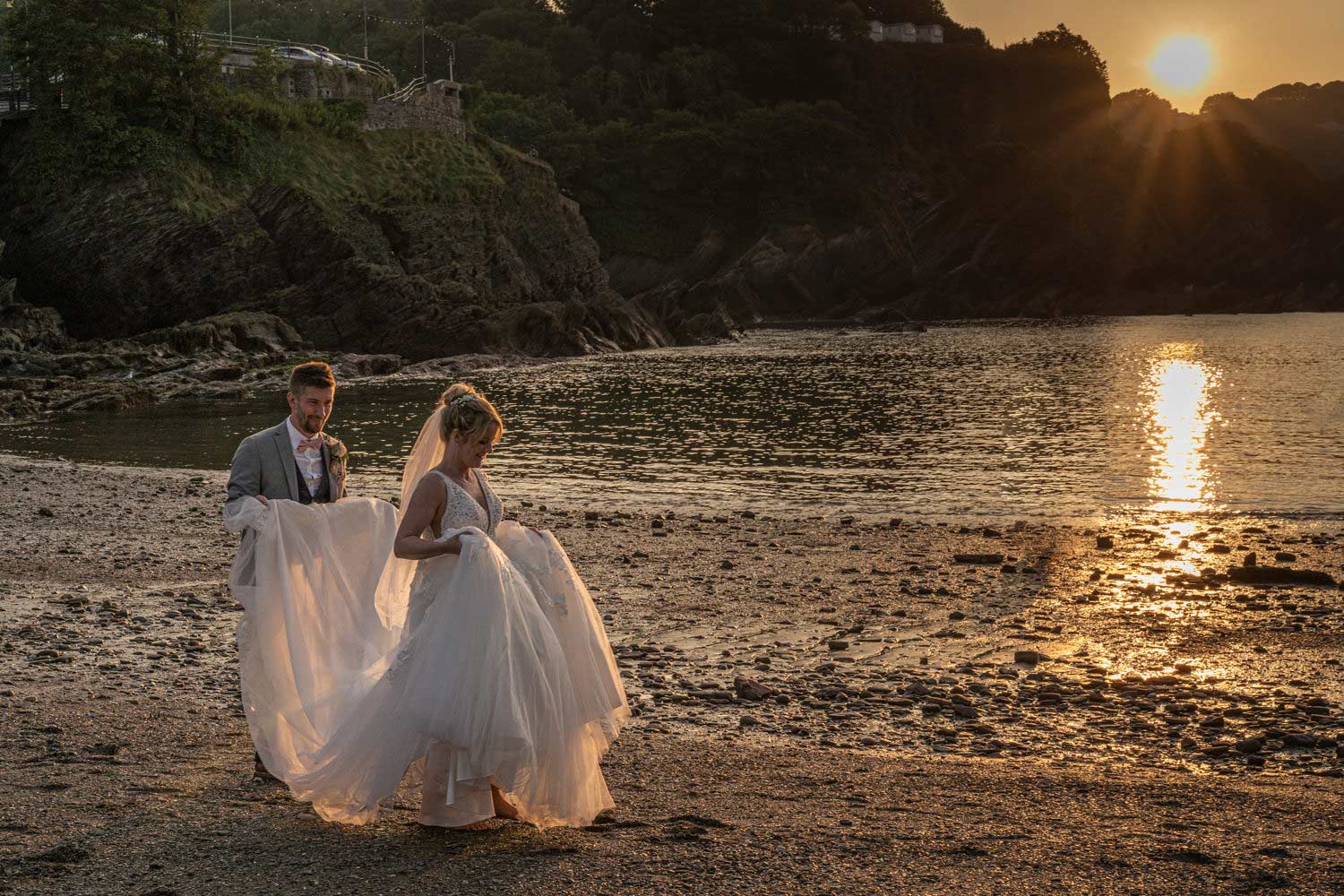 north devon coastal wedding bride and groom walking on beach at sunset