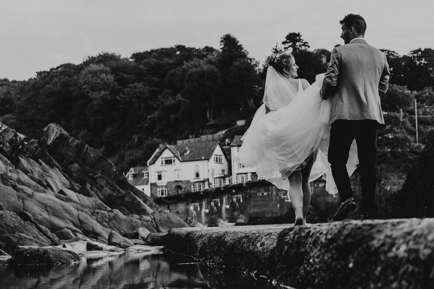 combe martin north devon coastal wedding bride and groom walking along coastal path. black and white picture. 